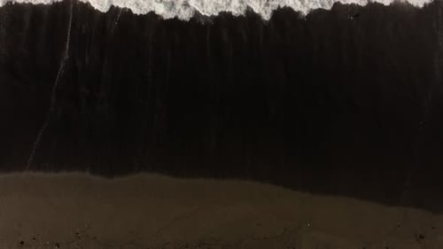 Aerial View of Waves Crashing on Black Sand Beach. Long Static Shot.