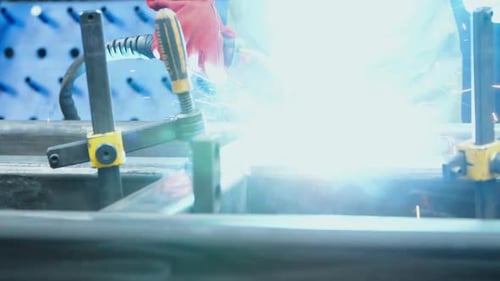 Industriearbeiter schweißt Metall mit vielen hellen Funken im Werk. Menschliches Schweißen