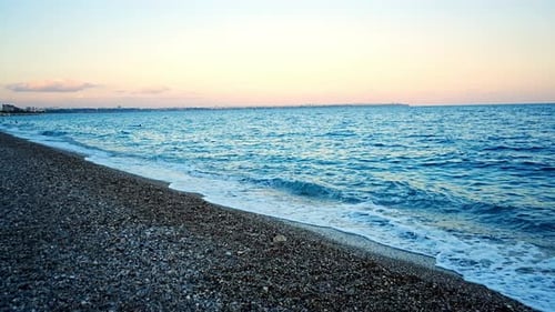 Steinstrand und Meereswellen bei Sonnenuntergang, Licht am Abend, Türkei