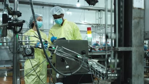 Deux ouvriers de l'industrie inspectent et contrôlent la bande transporteuse de l'usine.