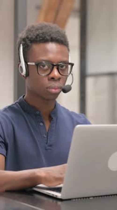 Young Man Working at Computer with Headset On