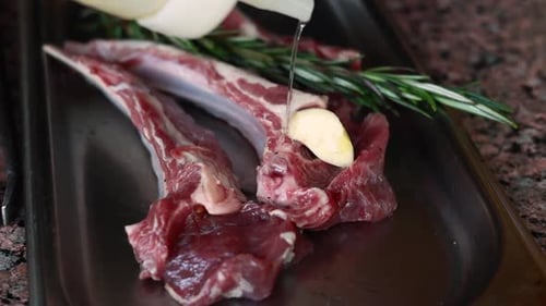 Raw Lamb Being Seasoned with Garlic and Rosemary