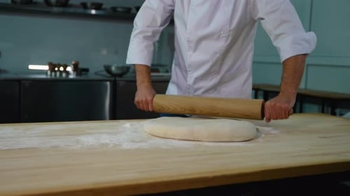 Chef Rolls Dough with Rolling Pin on Floured Table