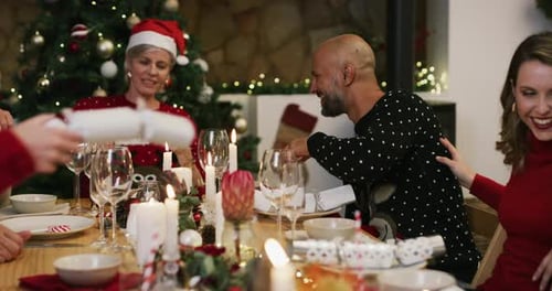 Family Celebrates Christmas Pulling Crackers at Table