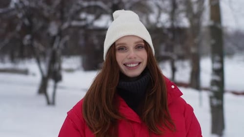 Smiling Woman in Red Coat in Snowy Park