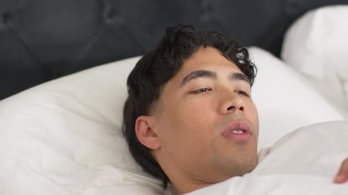 Matin léger et stimulant, homme allongé sur son lit, remuant, assis, se frottant la poitrine et s'étirant