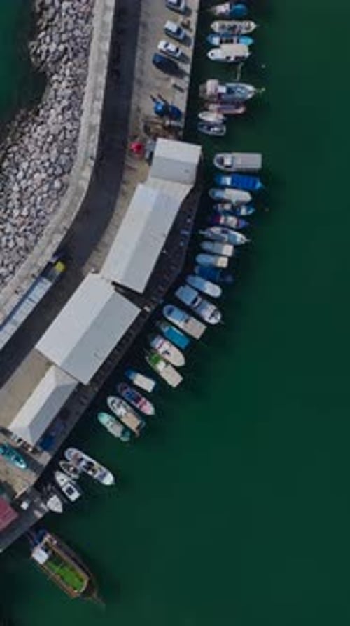 Vertical Video of a Port With Tourists Boarding Boats for a Coastal Tour Captured From a Drone With