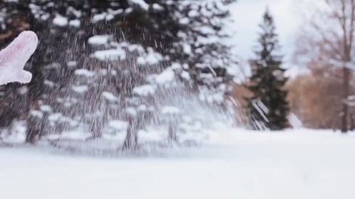 Mitten tosses handful of snow, winter background