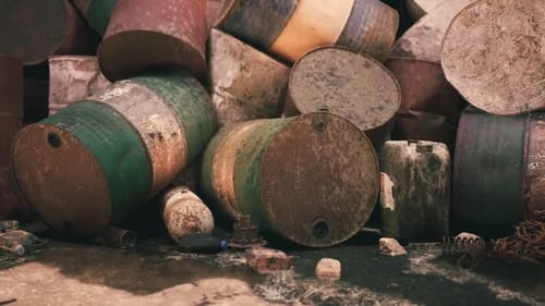 Rusting Barrels Scattered Across a Neglected Industrial Site in Daylight