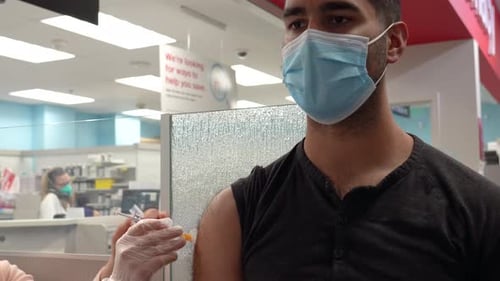 Man Receives Injection at Medical Clinic Wearing Mask