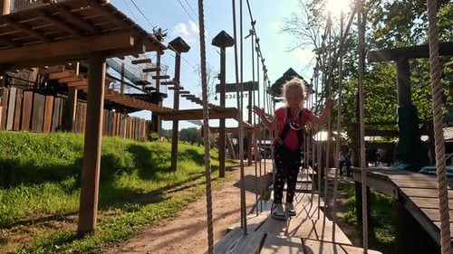 Happy Little Girl Playing in Tarzan Attraction on Playground in Amusement Park. Little Girls Enjoy P