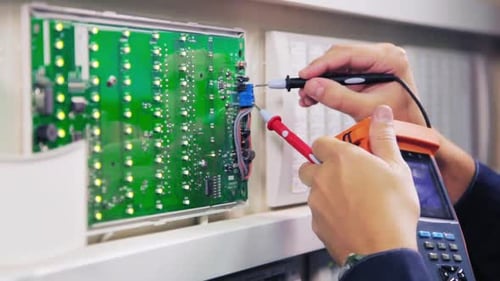 Man with Digital Meter Checks Circuit at Substation Closeup