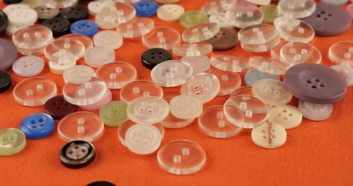 Plastic multi-colored buttons on an orange cotton fabric.