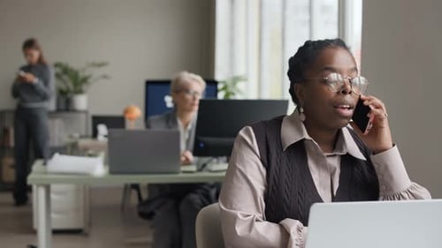 Young Black Female Manager Talking on Phone in Open Space Office