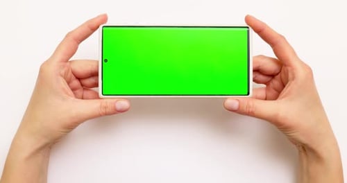 Woman's Hands Holding Smartphone with Green Screen on White Background