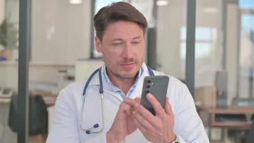 Male Doctor Using Smartphone in Hospital Office