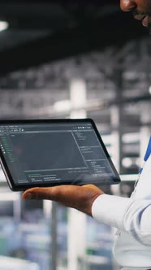 Vertical Video Close Up of Programmer Swiping on Tablet Display in Data Center Checking Code