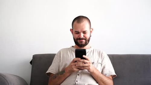 Young Adult Man Using Smartphone on Couch