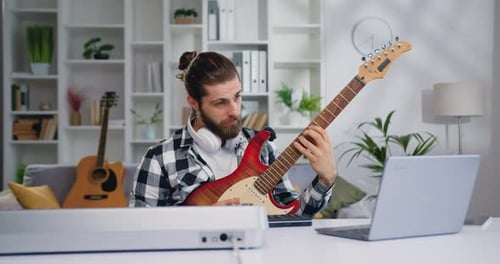 Man Plays Electric Guitar at Home Desk