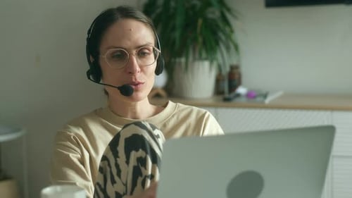 Woman Using Laptop and Headset for Video Call