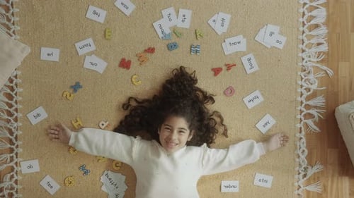 Girl Lying with Letters and Flashcards on Rug