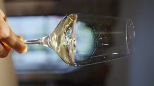 Hand Tilting Wine Glass with Golden Liquid
