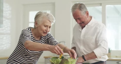 Loving Elderly Couple Preparing Salad Together in Kitchen