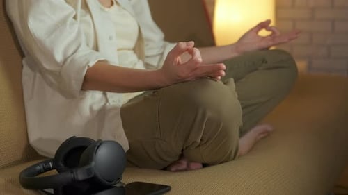 Woman Meditating on Couch with Headphones Nearby