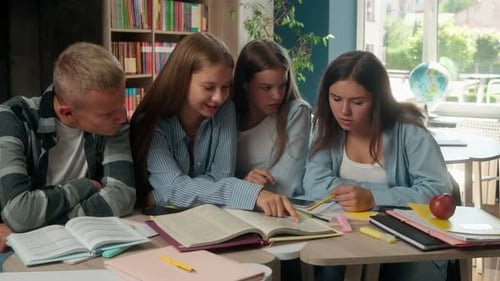 Vier Jugendliche, Klassenkameraden, lesen gemeinsam ein Buch, bereiten sich auf Prüfungen vor, machen Hausaufgaben, sprechen