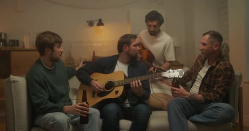Cara feliz e seu amigo tocando violão enquanto relaxam no sofá em uma despedida de solteiro no