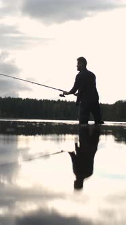 Silhouetted Fisherman Casts Line at Sunset