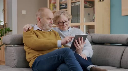Senior Couple Using Tablet Relaxing Together on Couch