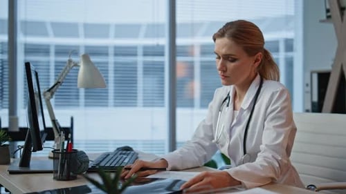 Woman Doctor Studying X-Ray at Desk