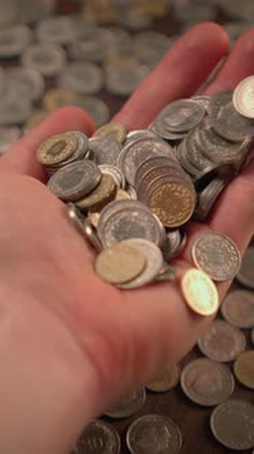 Hand Holds and Pours Silver and Gold Coins