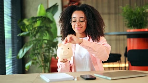 African American Woman Shows Happiness While Saving Money with a Piggy Bank
