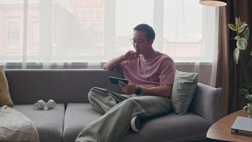 Young Adult Relaxing at Home with Tablet Device