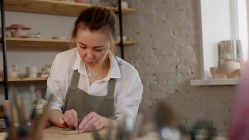 A Woman is Working on a Pottery Project in a Studio
