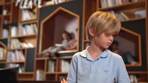 Attractive boy reading book while group of students learning behind. Erudition.