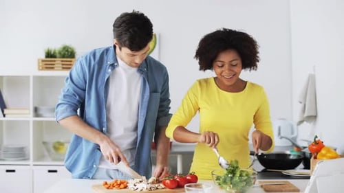 Happy couple cooking salad together in kitchen