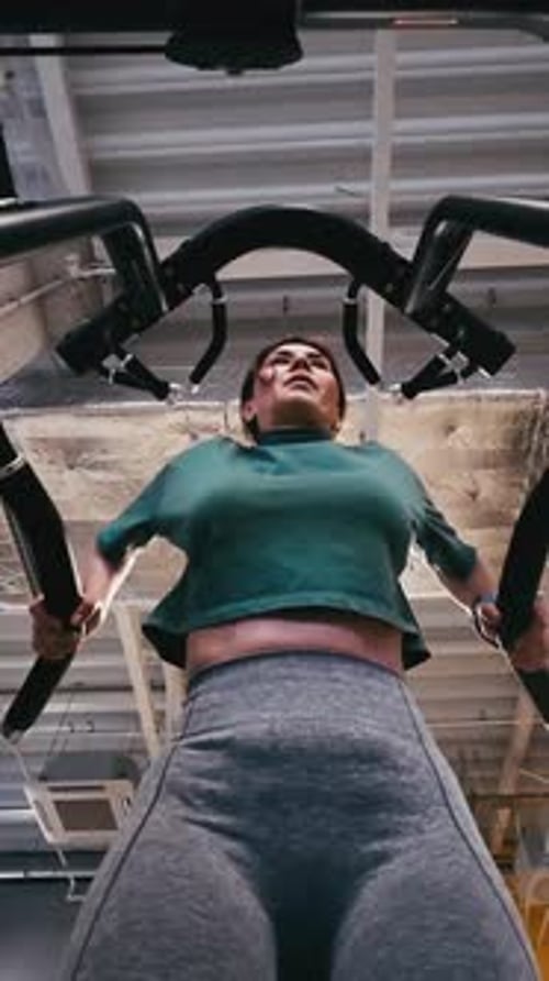 Girl Performs Assisted Dips On Parallel Bars In Gym Legs Supported