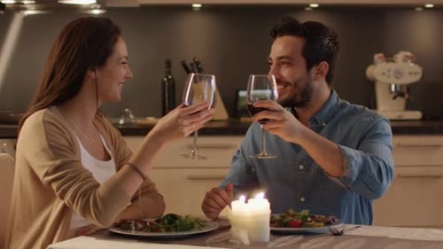Beau couple dînant aux chandelles dans la cuisine. Ils mangent, boivent et parlent. En guise de célébration