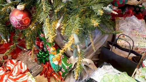 A Christmas tree close up with many presents wrapped - downward sliding shot