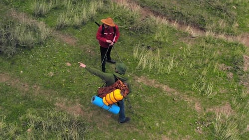Hikers Walking Along Trail Aerial View Couple Trekking Through Grassy Landscape Carrying Backpacks