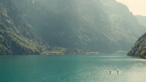 People in stand up paddle in sunny day, river landscape. Aerial flying backwards