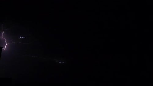 Flashes of lightning in the night sky among thunderclouds.