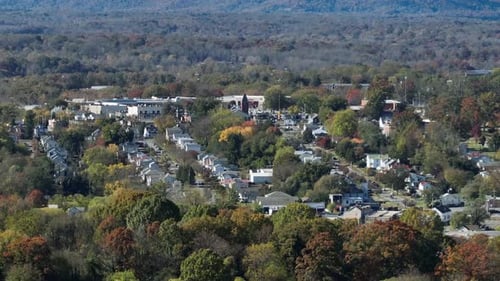 Aerial wide shot of American city neighborhood with colored trees in autumn season. Wide shot.