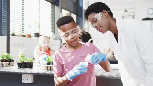 Diverse female teacher and happy schoolchildren having science class in school lab