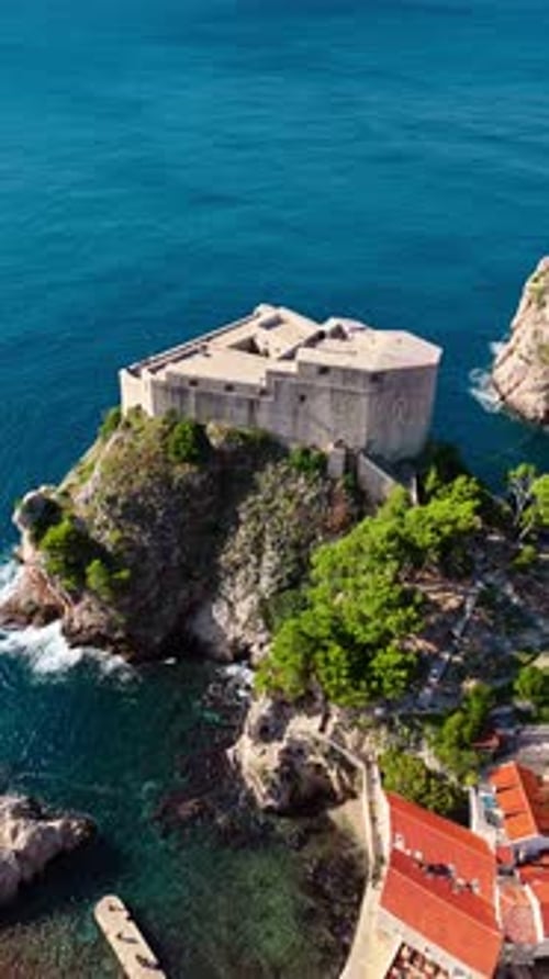aerial portrait drone shot approaching and panning down over fort lovrjenac on blue Adriatic Sea sun