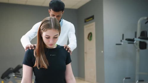 Trainer Hands Dumbbells to Woman During Workout Instruction in Modern Fitness Gym