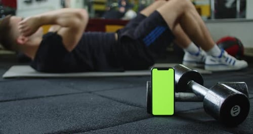 A Video Featuring a Green Screen Smartphone and a Man Doing Ab Exercises in the Background